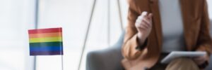 Small LGBTQ+ flag on the table in front of a female gender therapist