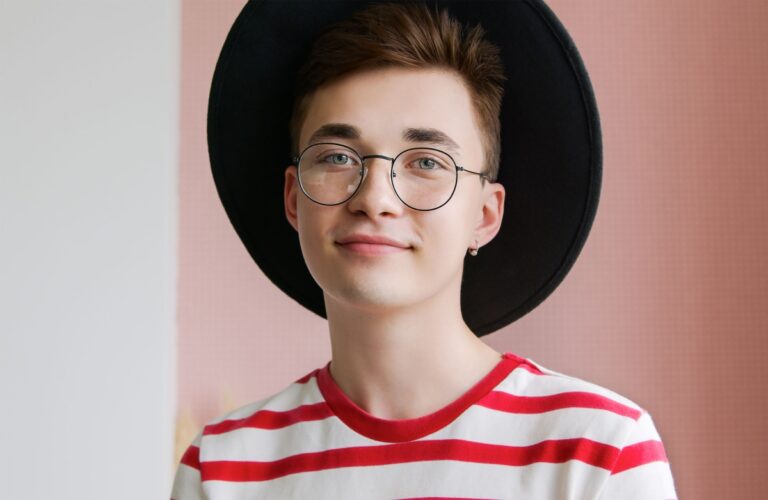 a young teenager wearing a hat, glasses, and a red striped shirt.