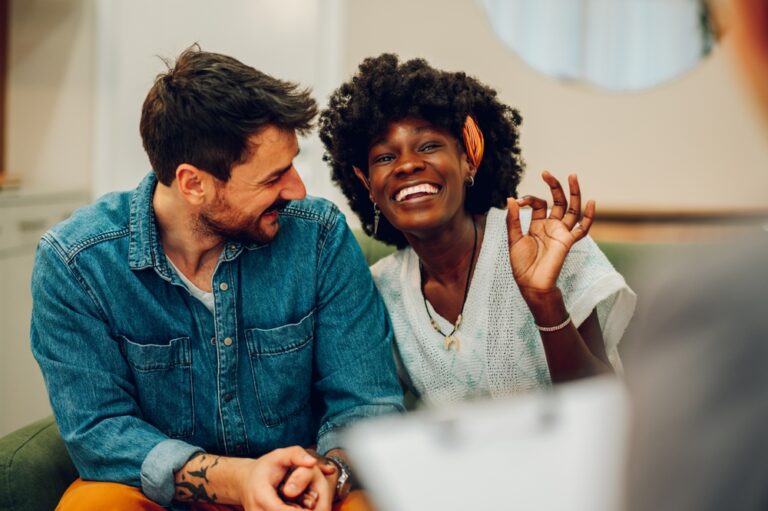 A smiling, laughing biracial couple in sex therapy