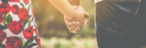 husband and wife holding hands as they walk toward a field of flowers